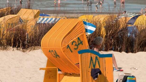 Une chaise de plage portant le numéro 134, entourée de parasols et avec des personnes en arrière-plan.