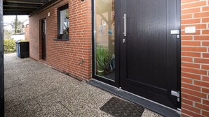 Un bâtiment en briques avec une porte en bois sombre et une fenêtre.
