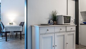 Une cuisine moderne avec des meubles blancs, un four à micro-ondes et une petite plante en pot.