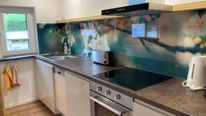 A modern kitchen with a built-in oven, a microwave, and a coffee maker. - Holiday Home Chalet on the Castle Hill (Brotterode-Trusetal)