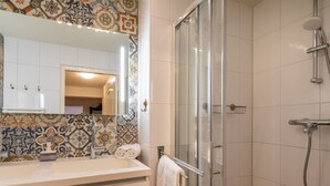 A bathroom with a shower, a sink with a mirror, and a towel rack. - Beautiful Bungalow With Garden (Biggekerke)
