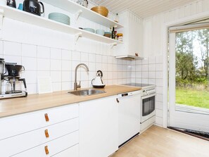 A modern kitchen with white cabinetry, a stainless steel sink, a kettle, a coffee maker, and a built-in oven. - 6 Person Holiday Home in Hals (Hals)