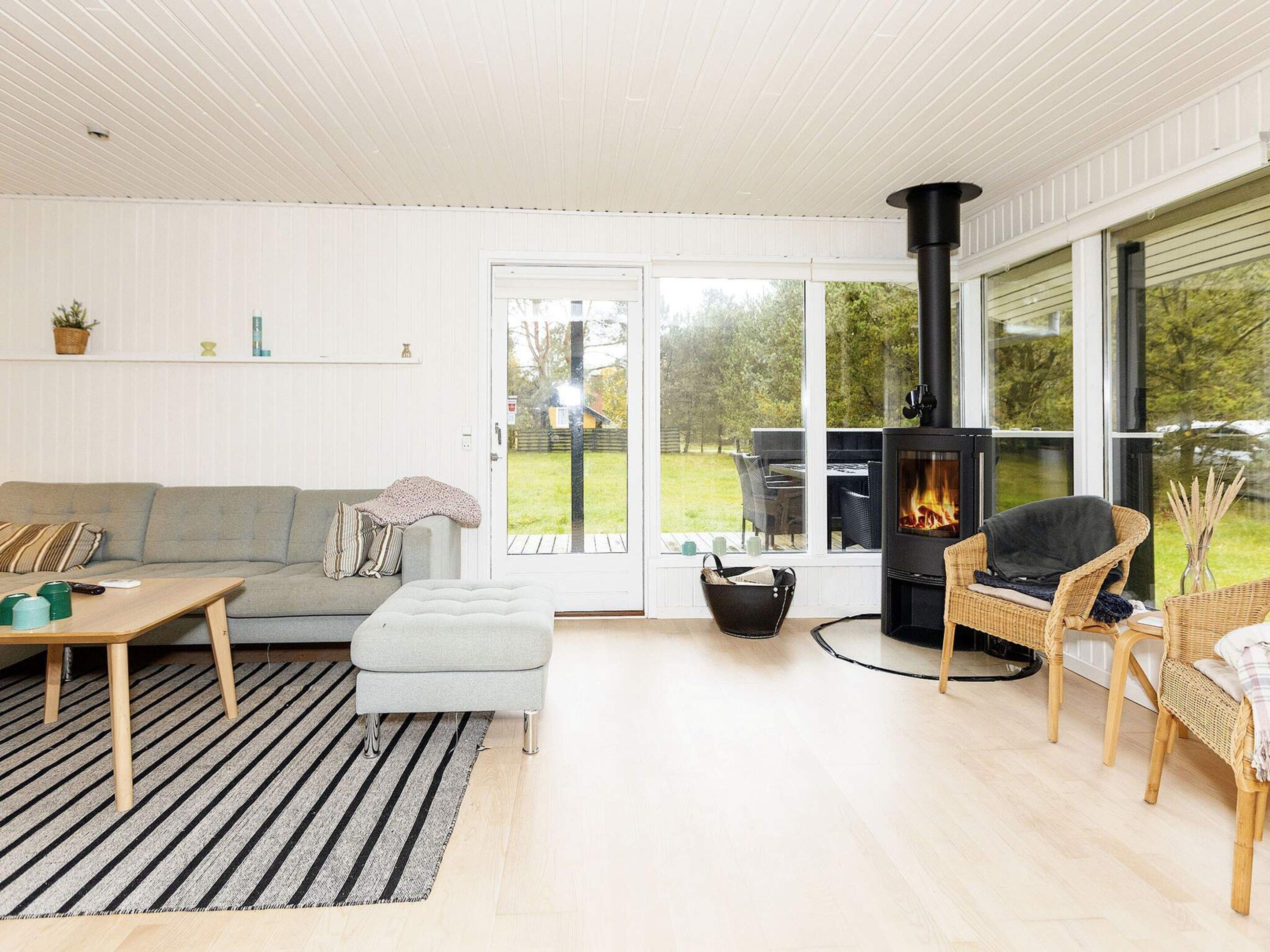 A modern living room with a sofa, a table, a fireplace, and a view of the outdoors.