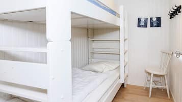 Habitación con literas, una silla y dos adornos en la pared.