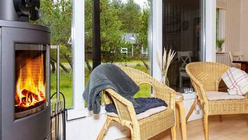 A room with a wood-burning stove, wicker chairs, and a view of the outdoors.