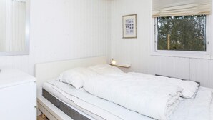A white room with a bed, a bedside table, a window, and a framed picture on the wall. - 6 Person Holiday Home in Hals (Hals)