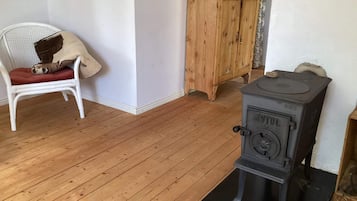 Ett rum med en vit stol, ett träskåp och en svart spis.
