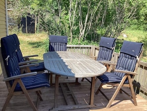 A wooden deck with a round table and four chairs with striped cushions. - 6 Person Holiday Home in Olofstrom (Olofström)