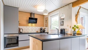A modern kitchen with a central island, built-in appliances, and a wooden ceiling. - 6 Person Holiday Home in Henne (Henne)