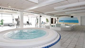 Ein großer, überdachter Pool mit Whirlpool, Liegestühlen und einem Wandgemälde.