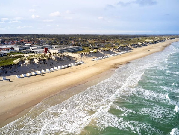 Un hotel frente al mar con una extensa playa de arena y olas oceánicas.