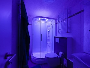 Une salle de bain avec une douche à parois de verre, des toilettes et un lavabo.