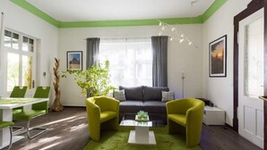 A modern living room with a sofa, two armchairs, a coffee table, and a dining area with chairs and a table. - Holiday Apartment Angela Koenig (Wernigerode)