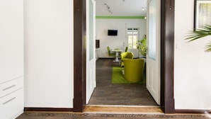 A hallway leading to a dining area with a green rug, a table, and chairs. - Holiday Apartment Angela Koenig (Wernigerode)