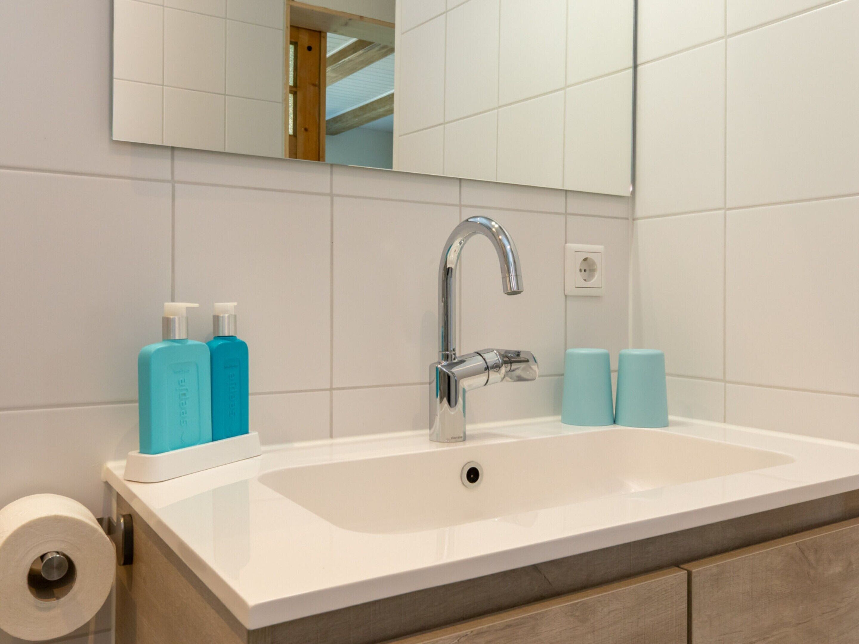 A bathroom with a white sink, a mirror, and two blue toiletries bottles.