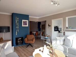 Ein modernes Wohnzimmer mit blauer Akzentwand, einem Essbereich und einer Küche.