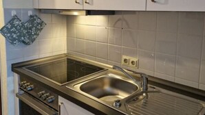 A kitchen with white cabinets, a double sink, a stove, and a microwave. - Waldresidenz Comfortable Holiday Residence (Unterkirnach)