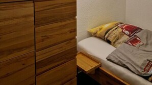 A bedroom with a wooden dresser, a bed with a patterned blanket, and a unique ceiling light fixture. - Waldresidenz Comfortable Holiday Residence (Unterkirnach)