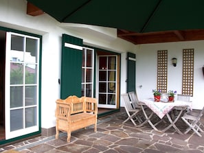 A covered patio with a wooden bench, a table with a tablecloth, and potted plants. - Chalet in Reith Near Ski Slopes (Reith bei Kitzbuehel)