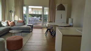 A modern living room with a sofa, ottoman, and a dining area with a table and chairs. - Apartment in Nieuwpoort for 6 Persons (Nieuwpoort)