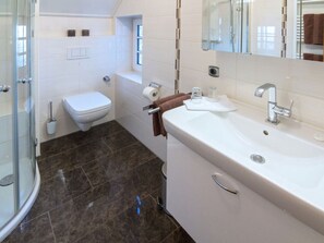 Ein modernes Badezimmer mit einer Duschkabine aus Glas, einer weißen Toilette, einer Badewanne und einem großen Waschbecken mit Spiegel darüber.