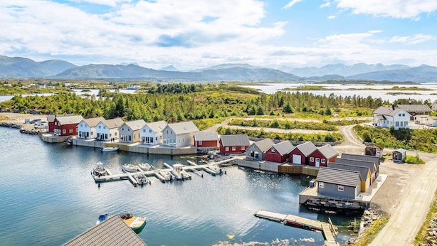 A coastal village with houses by the water, docks, and a clear view of mountains in the distance. - 6 Person Holiday Home in Bud (Averoy)
