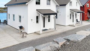 A row of white cabins with grey roofs, a wooden deck, and a rocky shoreline. - 6 Person Holiday Home in Bud (Averoy)