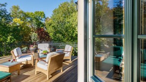 A deck with wicker furniture, a glass enclosure, and a view of trees. - Villa _master Suite Comfortable Vacation Home (Ilsenburg)