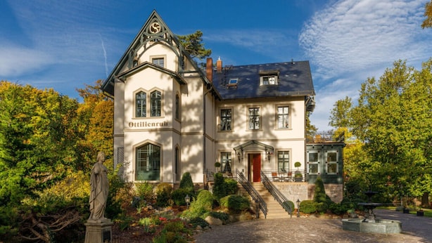 A historic building with a prominent entrance, a statue in front, and a well-maintained garden. - Villa _master Suite Comfortable Vacation Home (Ilsenburg)