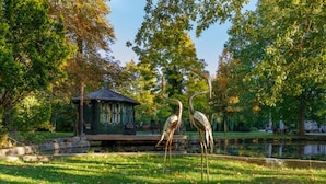 A park with a gazebo, a pond, and two herons. - Villa _master Suite Comfortable Vacation Home (Ilsenburg)
