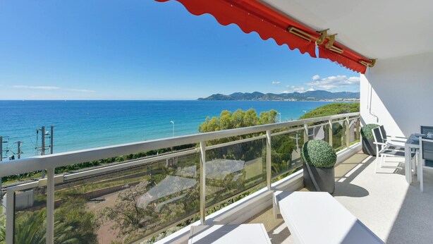 Een balkon met een helder uitzicht op de zee en verre bergen.