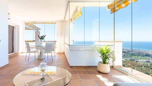 A modern balcony with a glass table, chairs, and a potted plant. - Belvilla by OYO La Zenaida II (Rincon de la Victoria)