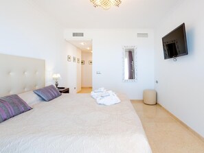 A hotel room with a large bed, a television, a mirror, and a bathroom visible through an open door.