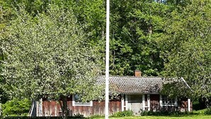 A rustic wooden house with a tiled roof, surrounded by lush greenery and a clear sky. - 4 Person Holiday Home in Anneby (Aneby)