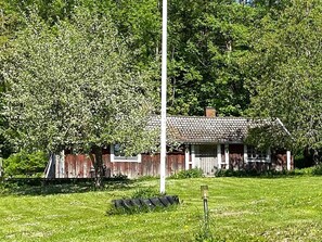 A rustic wooden house with a tiled roof, surrounded by lush greenery and a clear sky. - 4 Person Holiday Home in Anneby (Aneby)