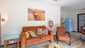 A living room with a brown sofa, a wooden coffee table, a blue refrigerator, and a wicker ceiling light fixture.