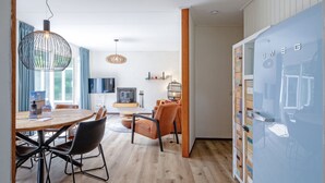 A modern living room with a dining area, wooden flooring, and a large blue cabinet with drawers.