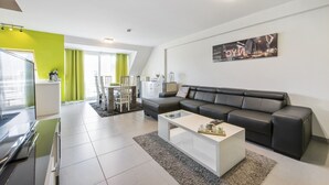 Un salon moderne avec un canapé en cuir noir, une table basse blanche et un tableau représentant un paysage urbain accroché au mur.