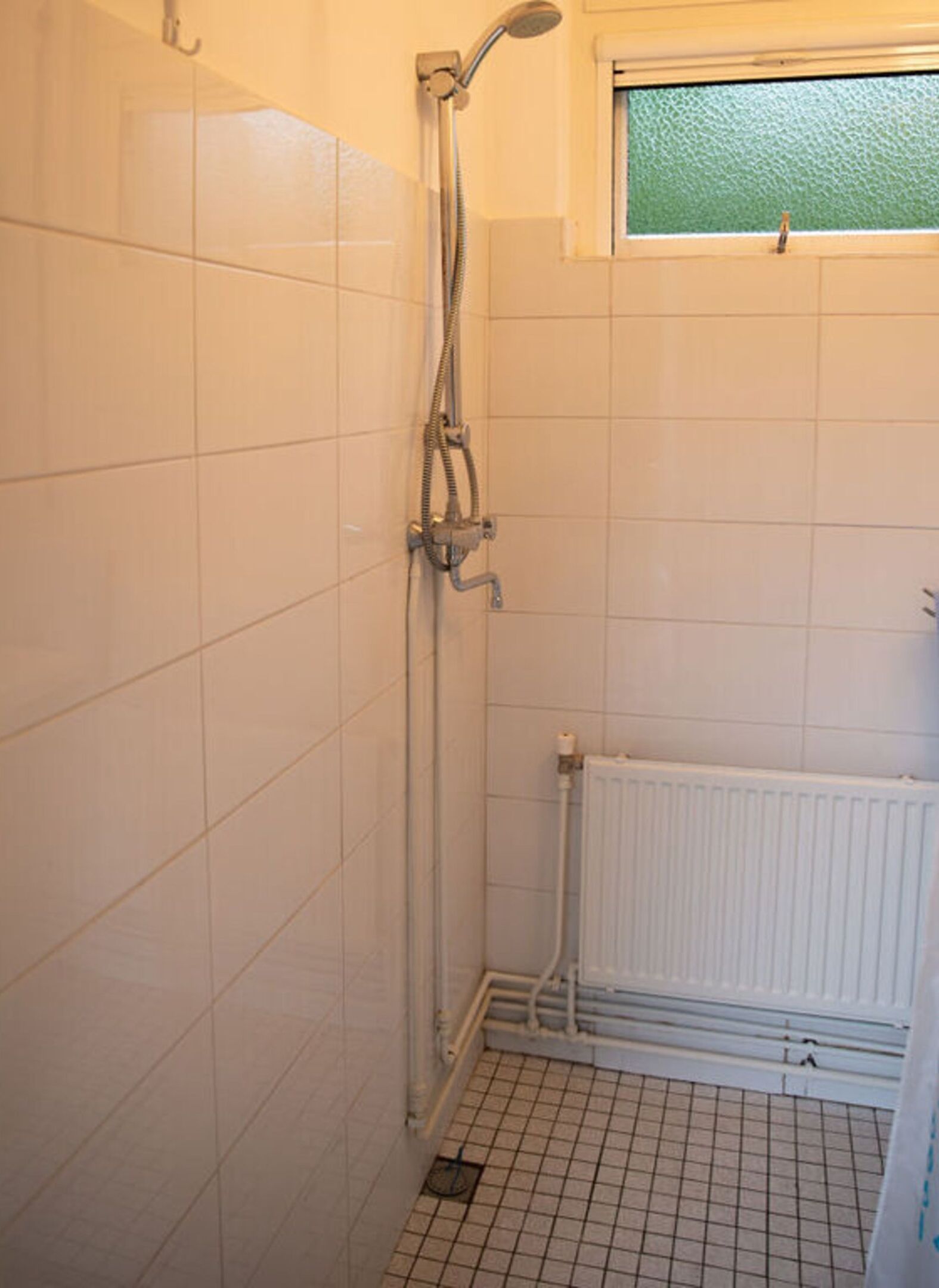Un pequeño baño con azulejos y una ventana sobre la ducha.
