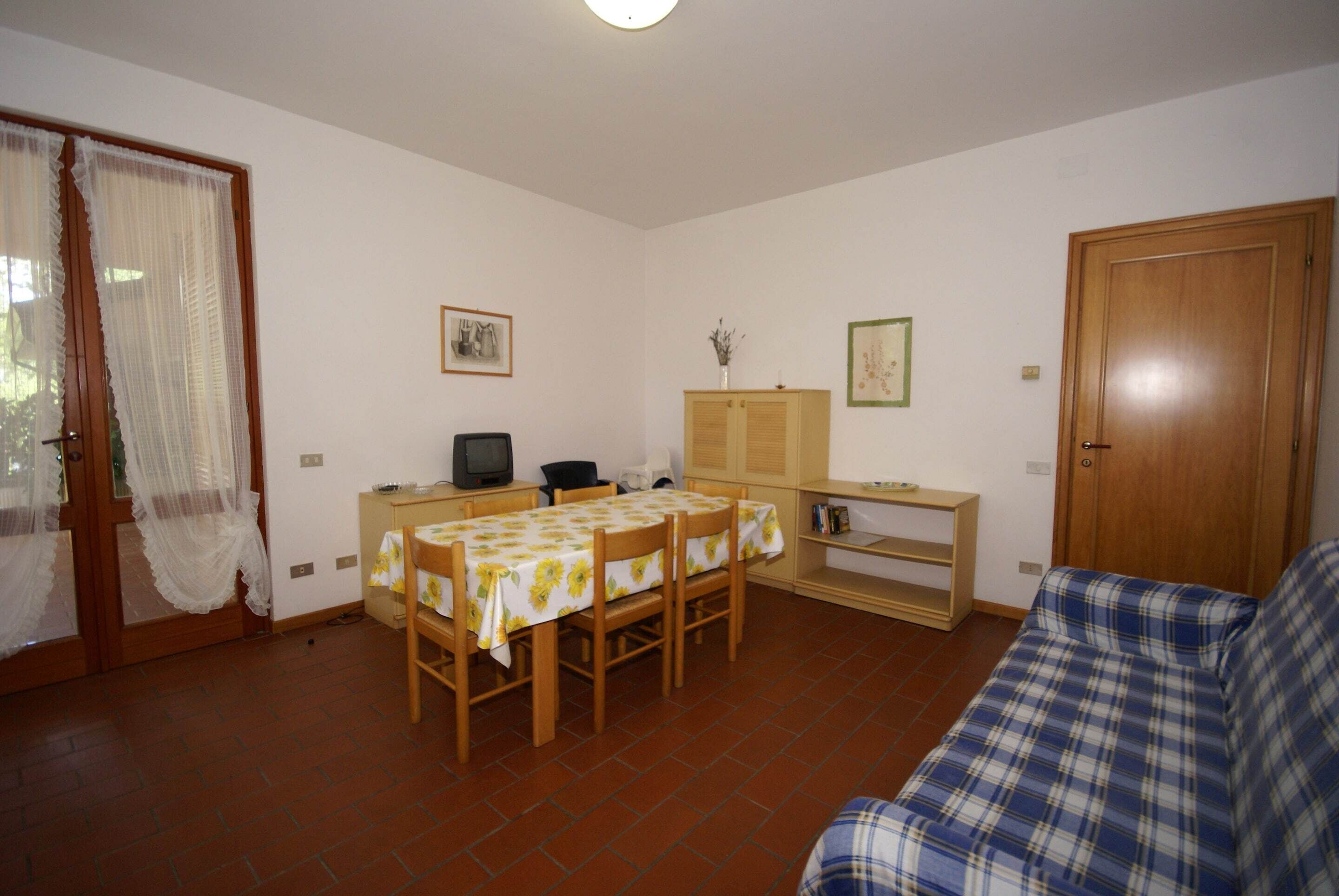 A living room with a dining table, a sofa, a TV, and a wooden cabinet.