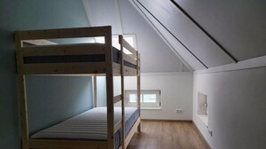 Une pièce avec un lit superposé, une petite fenêtre et un plafond en pente.