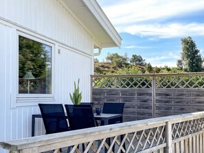 A patio with a table and chairs, a wooden fence, and a view of trees and hills. - 3 Person Holiday Home in Ronnang (Roennaeng)