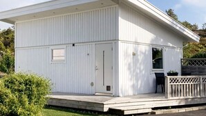 Een wit, laag gebouw met plat dak, een voordeur en een klein portaal.