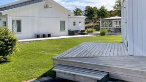 Een modern huis met een ruim terras, een overdekt buitengedeelte en een verzorgd gazon.