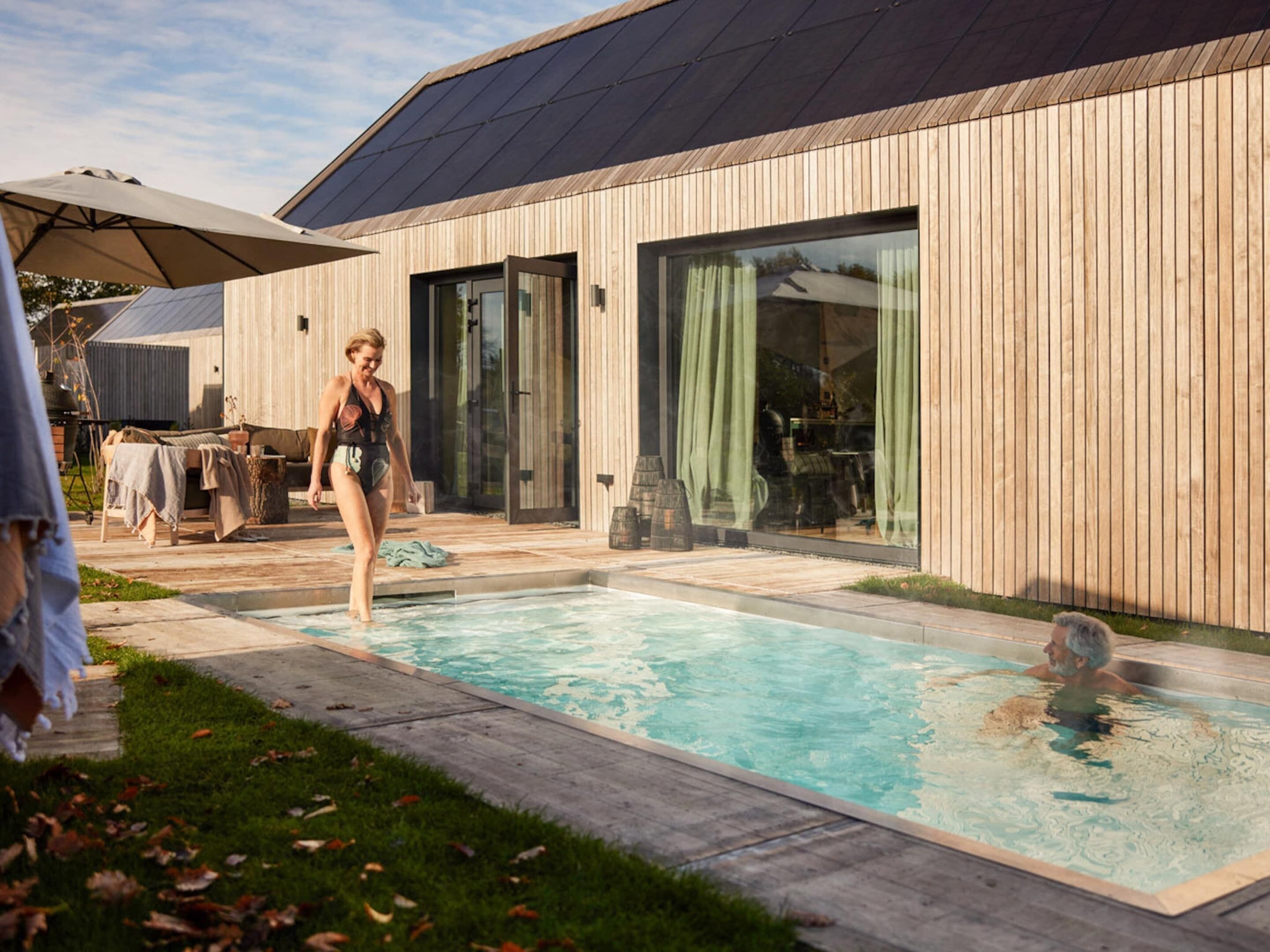 Una casa moderna con piscina, fachada de madera y ventanas amplias.