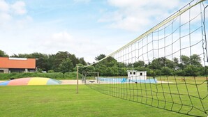 Ein Sportplatz mit einem mit Netz versehenen Tor, einem kleinen Gebäude und einer bunten Rutschenkonstruktion.