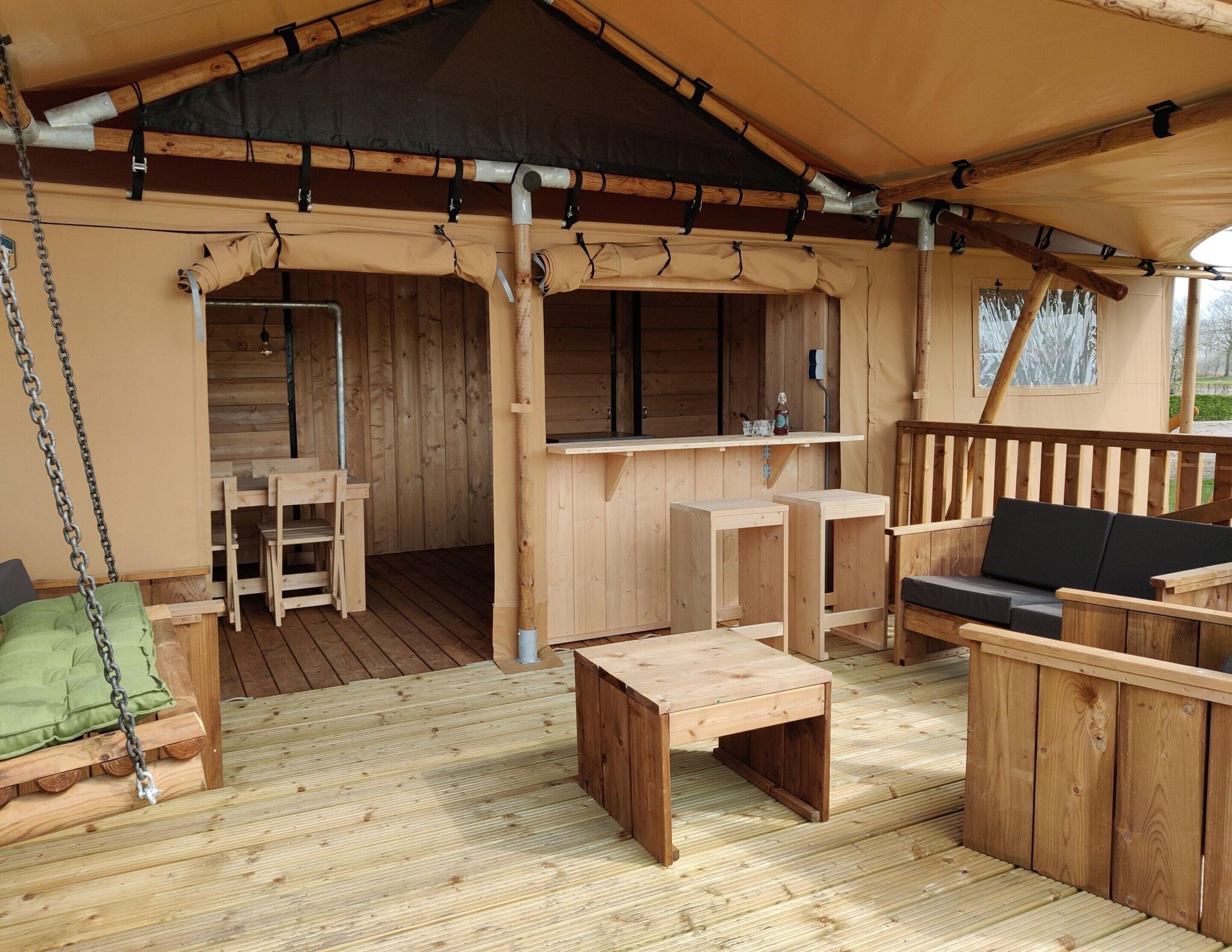 A wooden deck with a covered seating area, including a sofa and tables.
