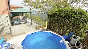 Ein achteckiger Pool mit einer Leiter, umgeben von einer Terrasse mit Stühlen und einem Tisch.