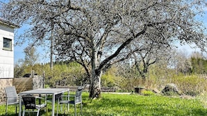 Un patio con una mesa, sillas, un árbol y un edificio al fondo.