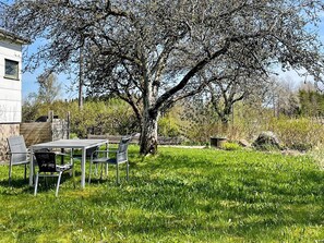 A patio with a table and chairs, a tree, and a building in the background. - 6 Person Holiday Home in Bollebygd (Bollebygd)